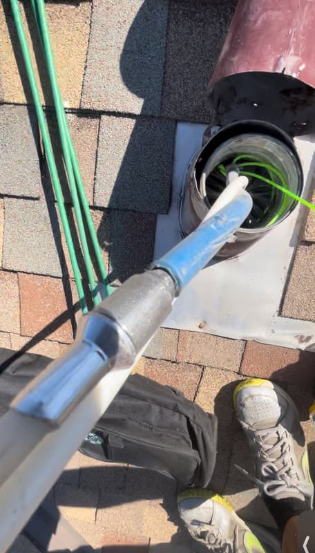 Cleaning rod inserted into rooftop dryer vent pipe