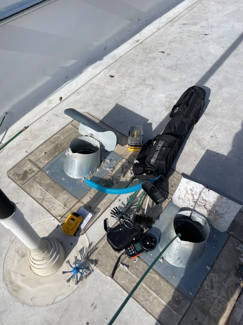 Service technician on commercial rooftop for dryer vent cleaning